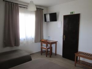 a bedroom with a bed and a table and a window at Baleal à Vista in Baleal