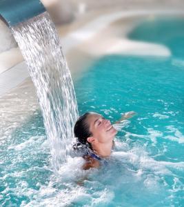 a woman in a swimming pool with a fountain at Hotel L'Oceane in La Cotinière