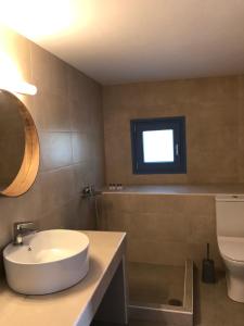 a bathroom with a sink and a toilet and a window at Vegera Apartment 'Ostria', Stavros Donoussa in Donoussa