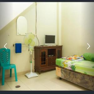 ein Schlafzimmer mit einem Bett, einem Ventilator und einem Stuhl in der Unterkunft Penginapan Sriwijaya in Tanjungpandan