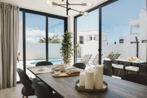 a dining room with a table and chairs and a pool at Villa Flamboyan in Yaiza