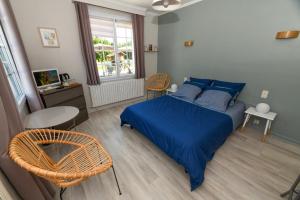 ein Schlafzimmer mit einem blauen Bett, einem Tisch und einem Stuhl in der Unterkunft Résidence Romaric in Jard-sur-Mer