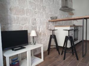 a living room with a tv on a table with two stools at Apartments Kut in Vis
