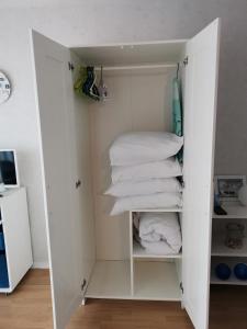 un armadio bianco con asciugamani bianchi di Studio "Voile de nacre" a Bernières-sur-Mer