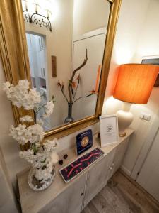 a vanity with a mirror and a lamp and flowers at BandBFirenze 8 Cittadella 8 in Florence