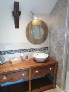 een badkamer met een wastafel en een spiegel bij Le Douétaux chambres d'hotes in La Baussaine