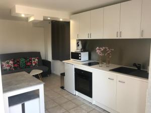a kitchen with white cabinets and a microwave and a couch at La perle rare in Le Grau-dʼAgde