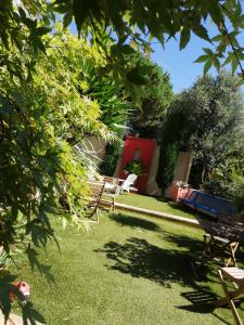 un jardín con sillas, árboles y césped en La Chamberte, en Villeneuve-lès-Béziers