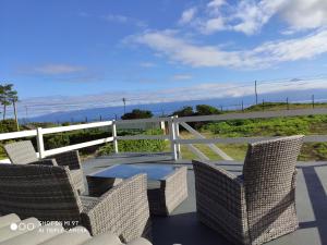 un patio con sillas de mimbre y una valla blanca en Varandas do Basalto en Queimada