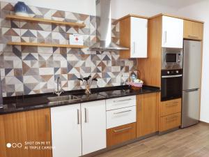 a kitchen with white cabinets and a black counter top at Varandas do Basalto in Queimada