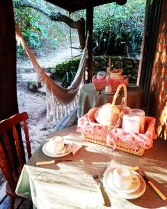 a table with a basket of food on a hammock at Pousada Rosa & Canela in Praia do Rosa