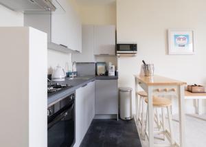 a kitchen with white cabinets and a wooden table at Serene in Ryde in Ryde