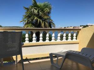 balkon z krzesłem, ogrodzeniem i palmą w obiekcie Apartments and Rooms Villa Luci w mieście Barbat na Rabu