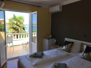 a bedroom with a bed with a view of the ocean at Apartments and Rooms Villa Luci in Barbat na Rabu