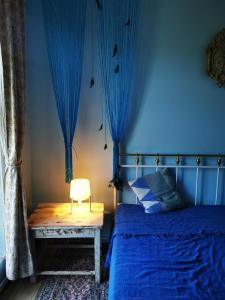a bedroom with a bed with blue curtains and a chair at Gold Sun Zelta Saule in Matkule