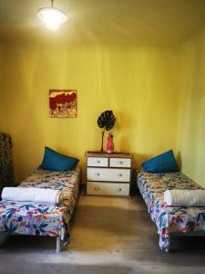 two beds in a room with yellow walls and a dresser at Gold Sun Zelta Saule in Matkule
