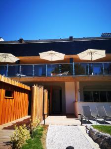 a house with chairs and umbrellas in front of it at L'Argalyde Esprit Pyrénées Wellness & Cycling in Ayzac-Ost