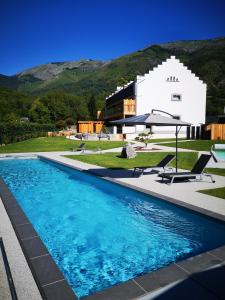 una piscina di fronte a un edificio con una casa di L'Argalyde Esprit Pyrénées Wellness & Cycling a Ayzac-Ost