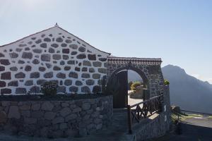 Casa Rural Isla de Cuba في تيخيدا: مبنى حجري مع بوابة وجدار حجري