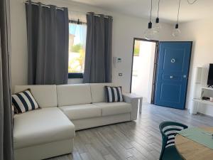 a living room with a white couch and a blue door at Rosalia Homestay - Levante Apartment in Cinisi