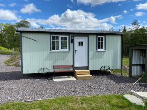 a green shed with a bench and a door at Wee Highland Hideaway Hut in Dalmally