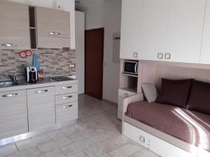 eine Küche mit weißen Schränken und ein Bett in einem Zimmer in der Unterkunft EV 37 in Germignaga
