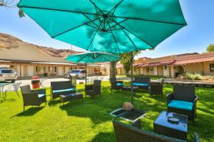 eine Terrasse mit Stühlen, Tischen und einem Sonnenschirm in der Unterkunft Adventure Inn Moab in Moab