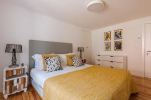 a bedroom with a large bed with a yellow blanket at Hidden Gem in Principe Real in Lisbon