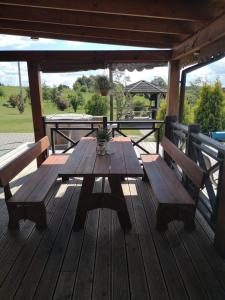 una mesa de madera en una terraza con 2 bancos en Abromiškių Sodyba, en Elektrėnai