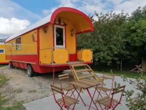 a red and yellow trailer with chairs and tables at Guesthouse Gjoel in Gjøl