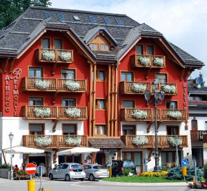 un edificio rojo con balcones y coches estacionados frente a él en Hotel Belmonte, en Roana