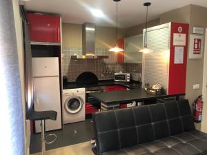 a kitchen with red cabinets and a washer and dryer at La Capital del Jerte in Plasencia