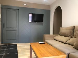 a living room with a couch and a tv on a wall at La Capital del Jerte in Plasencia