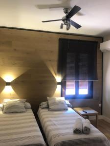 two beds in a room with a ceiling fan at La Capital del Jerte in Plasencia