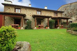 a large stone house with a green yard at Apartamentos Rurales Los Brezos* in Cotillo