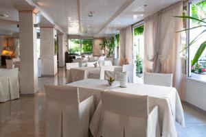 restauracja z białymi stołami, krzesłami i oknami w obiekcie Hotel Mauritius Sentirsi come a Casa w mieście Riccione