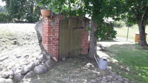 eine Backsteinmauer mit einer Holztür neben einem Baum in der Unterkunft Sielska Chata in Fabianki