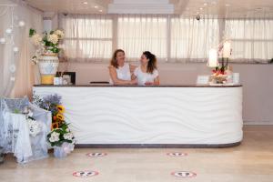 リッチョーネにあるHotel Mauritius Sentirsi come a Casaの結婚式のカウンターの後ろに立つ二人