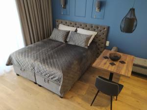 a bedroom with a bed and a wooden table at Apartamenty Wygoda Jurowiecka in Białystok