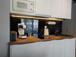 a kitchen with white cabinets and a white microwave at Apartamenty Wygoda Jurowiecka in Białystok