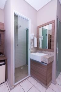 a bathroom with a sink and a mirror at Kennedy Slim Hotel in São José