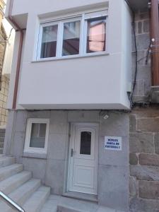 uma casa com uma porta branca e um sinal nela em Dúplex Costa de Fisterra I em Finisterre