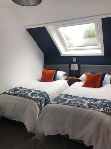 two beds in a room with a window at Fox Cottage in Moffat