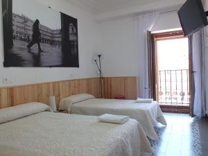 a bedroom with two beds and a tv on the wall at Los Angeles Plaza in Salamanca