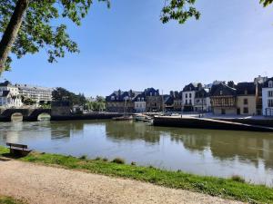 a river in a city with buildings and a bridge at Appartement Port de St Goustan in Auray