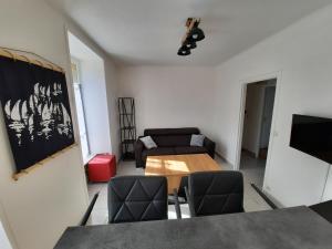 ein Wohnzimmer mit einem Tisch, Stühlen und einem Sofa in der Unterkunft Appartement Port de St Goustan in Auray