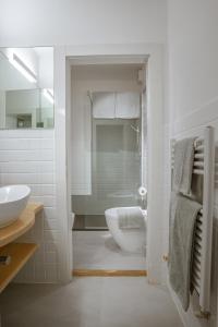 Baño blanco con lavabo y aseo en B&B S. Trinità 18 Suites & Rooms en Trento