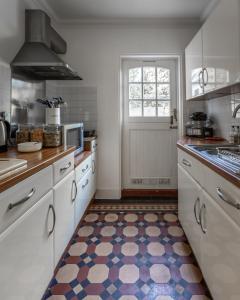 a kitchen with white cabinets and a colorful floor at Cranborne House in Poole +26 photos