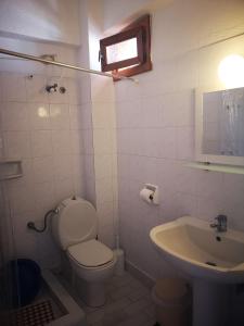 a white bathroom with a toilet and a sink at Rodi Apartments in Polykhrono