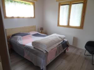 a bedroom with a bed and two windows at Chalet neuf 6 personnes in Mont-Saxonnex